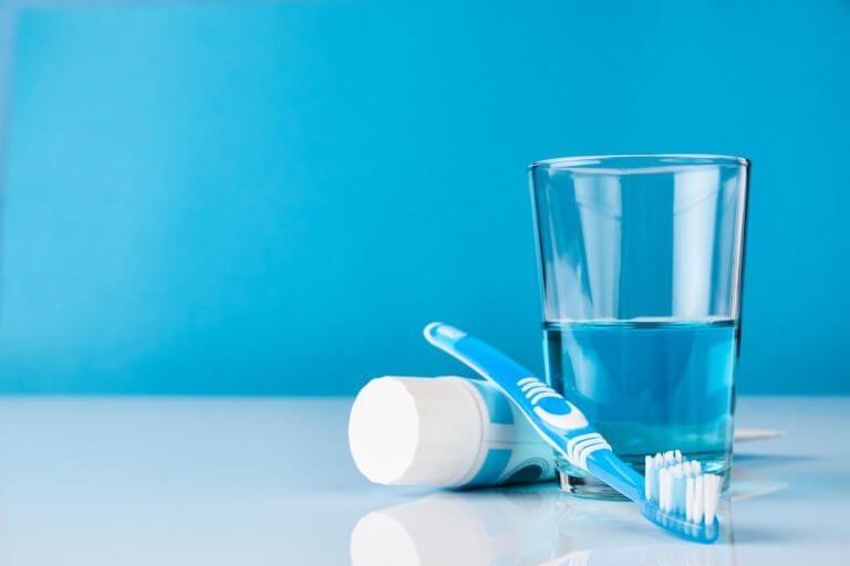 Stock image showing mouth wash , glass half filled with mouth wash and tooth brush