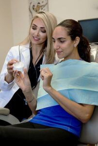 A dentists shows a patient a tooth mold for their Invisalign Beverly Hills CA treatment